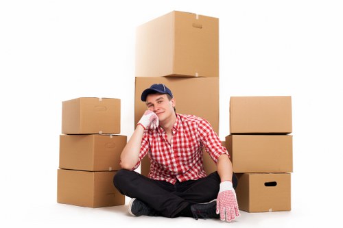 Professional movers carrying furniture through a narrow flat staircase in Ealing